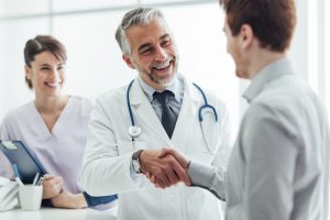 A doctor shaking hands with a patient and smiling